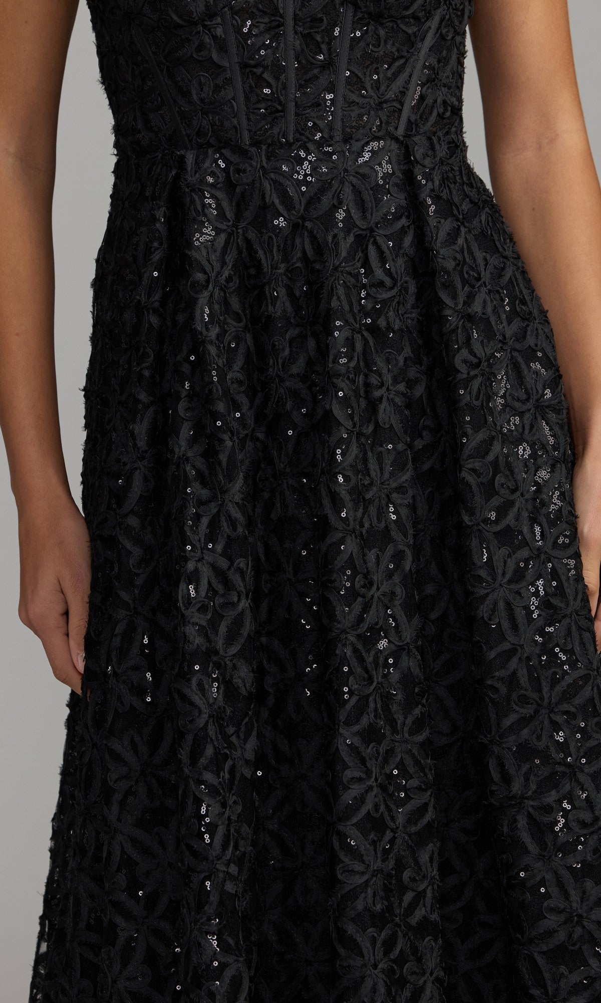 A person wearing the Mac Duggal 56286 long formal dress in black lace with floral patterns and sequins, shown from the shoulders to the knees.